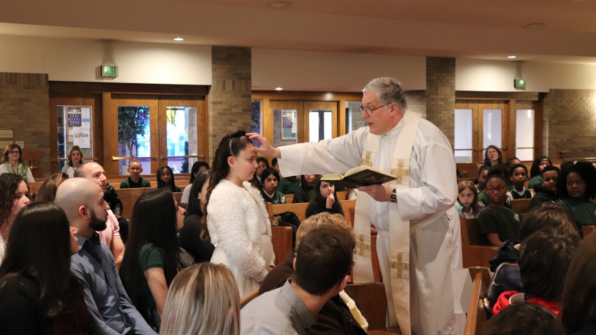 Father James Meade anoints a student in December 2019