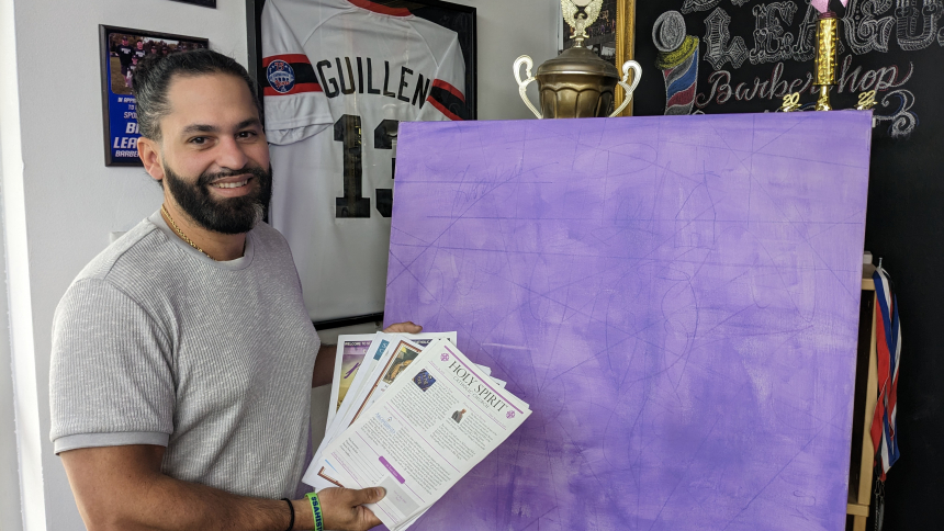 While in his Hammond barbershop on April 17, Federico "Freddie" Pintor displays the bulletins he collected while standing before a light "purple washed' canvas.