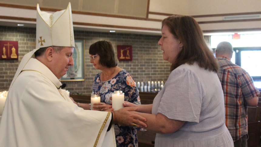 Bishop Robert J. McClory presents Lisa Anderson, of St. John the Evangelist in St. John, with a lighted candle in remembrance of a child lost too soon during the annual Remembering the Children Pregnancy and Infant Loss Memorial Mass hosted by the Diocese of Gary on May 7. Families who suffered a miscarriage, or lost a stillborn infant or young child, were invited to St. James the Less in Highland to mark International Bereaved Mother's Day. (Marlene A. Zloza photo)