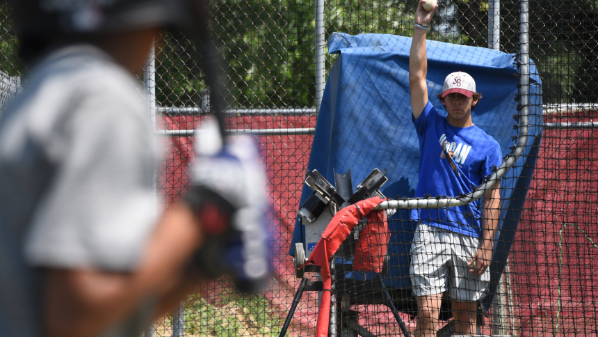 Senior Andrean High School baseball player Tyler Peller (right) signals a young batter to prepare for the pitching machine toss during the 59ers summer baseball camp on June 21 at AHS in Merrillville. Despite Peller's three hits and two RBI in the state championship game in Indianapolis on June 16, the 59ers lost to the Silver Creek High School Dragons of Sellersburg, 2-4. (Anthony D. Alonzo photo)