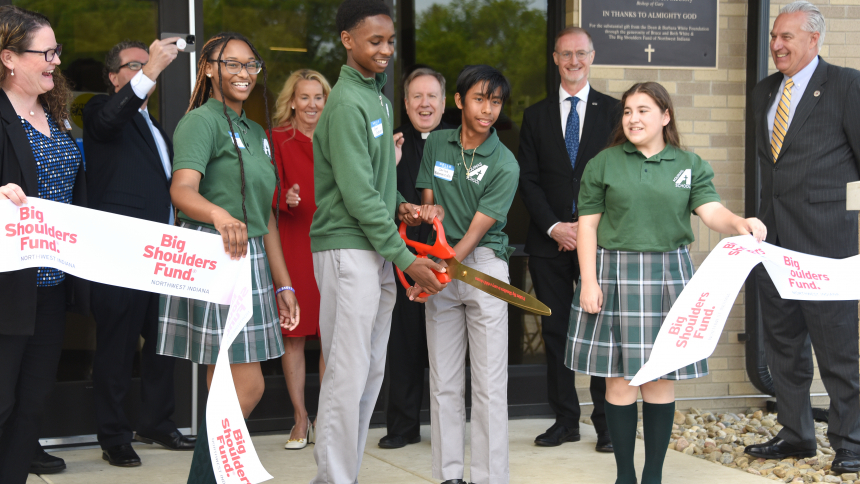 Students at Aquinas Catholic School hold oversized scissors as they cut a ribbon during a celebration marking the official opening of a 