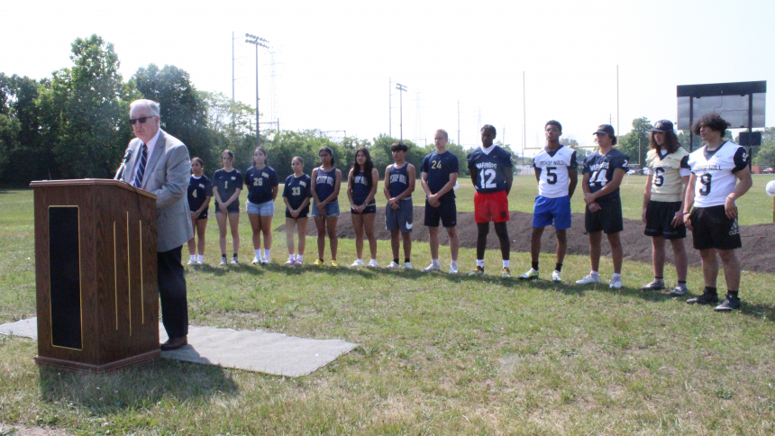 With Warrior football and girls soccer players backing him up, Bishop Noll Institute president Paul Mullaney (Noll '77) explains the outdoor athletic facilities upgrade before groundbreaking ceremonies took place on June 20 at the Hammond school, the largest of the Diocese of Gary's three high schools. Phase I of the $9 million project will involve a new turf field for football and soccer, the addition of a regulation eight-lane track and field event areas, plus a grandstand/press box with seating for 1,500