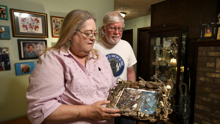 Diane McKern (left), vice president for the Society of Saint Vincent de Paul, District Council of Gary, views homemade family art with her husband Dan McKern (right) at the couple's home in Hammond on May 25. A convert to the Catholic faith and longtime charitable advocate, Diane McKern is recignized by Our Lady of Perpetual Help parishioners and faithful throughout the diocese as a generous and innovative leader. (Anthony D. Alonzo photo)
