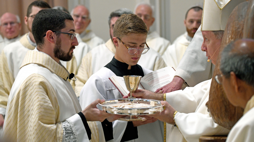 Bishop Robert J. McClory (right) presents newly ordained Father Robert Ross (left) gifts of a chalice and communion plate as seminarian Gianni Ditola (center) looks on during the Mass of Ordination to the Priesthood and Diaconate on June 3 at the Cathedral of the Holy Angels in Gary. Also at the liturgy, Steven Caraher, of Munster, and Zachary Glick, of Highland, were ordained as transitional deacons. (Anthony D. Alonzo photo)