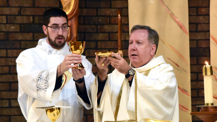 During a parish visit at St. Stephen, Martyr, Bishop Robert J. McClory (right) raises the paten during the Eucharistic Prayer as Deacon Robert Ross raises the chalice, on May 7 at the Merrillville church. During the liturgy, the bishop blessed sacred vessels and vestments that Deacon Ross will use after he is ordained in June. (Anthony D. Alonzo photo)