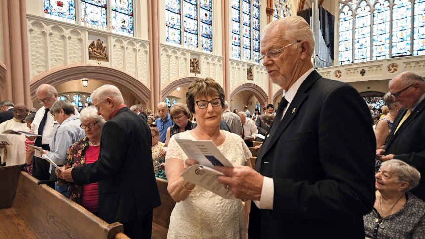 Caren and Ken Jankowski (front) pray along with the program for the 40th Annual Wedding Anniversary Celebration on the Solemnity of the Most Holy Trinity, June 4, at the Cathedral of the Holy Angels in Gary. The Jankowskis marked 55 years of marriage at the Mass where Bishop Robert J. McClory presided and preached about the mystery of the Holy Trinity as a Godly relationship and that couples of faith "with the grace of the sacrament intertwining and flowing through you, you become an expression of the very 