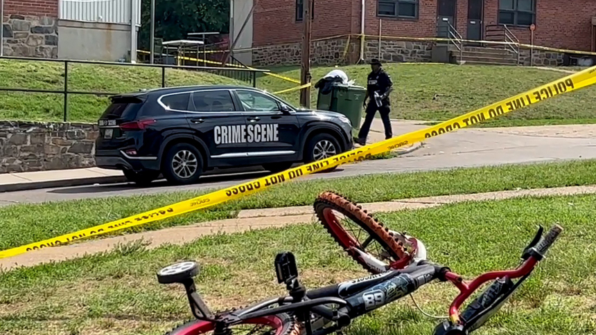 A child's bicycle, seen in a still image from video, lies on a lawn as a police office walks down a residential street in Baltimore July 2, 2023, after a mass shooting at a Fourth of July holiday weekend block party. Archbishop William E. Lori of Baltimore asked for prayers for the victims after the mass shooting left two dead and injured more than two dozen others, most of whom were teens. (OSV News photo/Reuters)