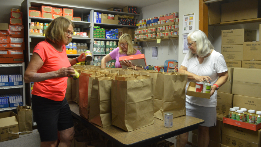 Margie Slamkowski, Kim Milner and Gina Faith begin to bag grocery items that were distributed as part of the food panty at Nativity of Our Savior in Portage. The pantry assists more than 400 individuals/families each month. (Erin Ciszczon)