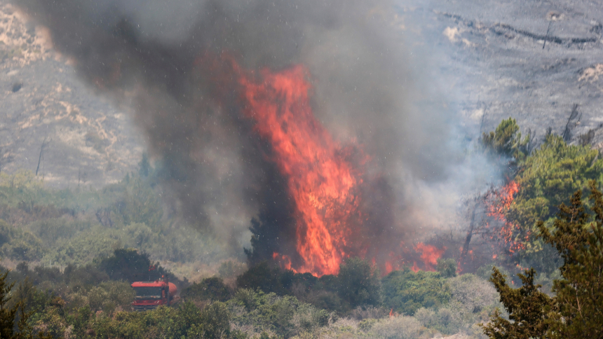 Flames rise next to a firefighting truck as a wildfire burns near the village of Vati, on the island of Rhodes, Greece, July 25, 2023. Heat waves all over the globe have seen Greece, Italy and Spain record all-time high temperatures with the heat index in several Middle Eastern countries reaching 152 degrees Fahrenheit, near the limit of human survival. (OSV News photo, Nicolas Economou, Reuters)