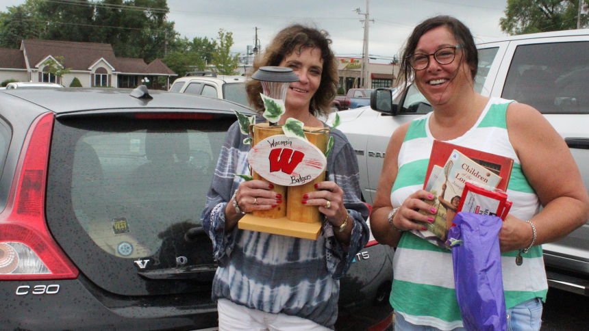 Friends Rosemary Swank (left) and Meredith Babcock, both of Lowell, head to their car with their purchases after visiting the Holy Name Local Market on Aug. 12 in Cedar Lake. Babcock, a parishioner, bought books and jewelry and praised the "friendly atmosphere" at the fundraiser for parish ministries, a first-time event that will likely become annual. (Marlene A. Zloza photo)