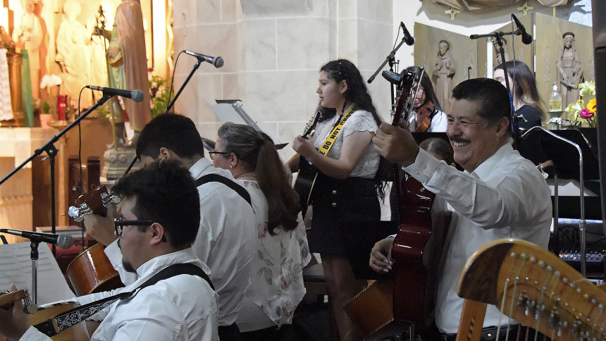 Gaudencio Martinez (right), a native of Mexico, strums his guitar along with a group of novice musicians who perform liturgical songs during a Sunday evening Mass on Aug 6. at St. Casimir in Hammond. The instrumentalists and singers ranging from young children to seniors began training in June with Martinez, who has brought his musical crash course to St. Casimir for more than 15 summers. (Anthony D. Alonzo photo) 
