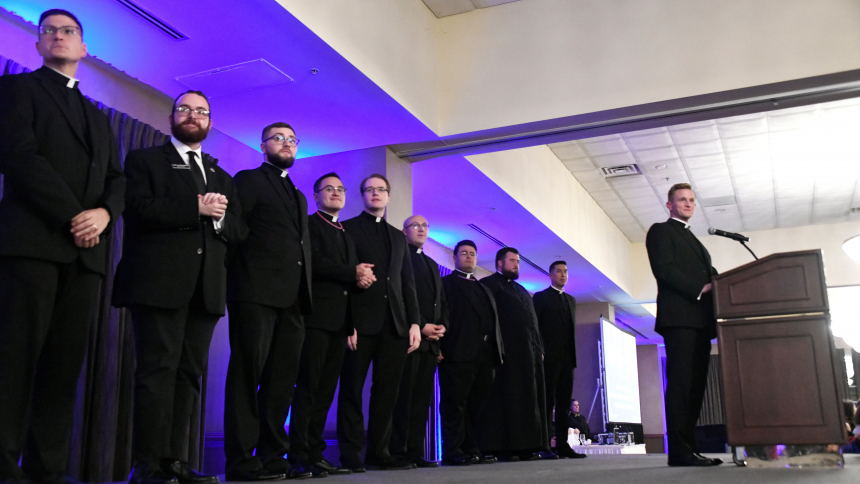 Father Nathaniel Edquist (right), diocesan vocations director, speaks of the commitment to serving the Church exhibited by the seminarians on stage (along with assistant vocations directors) at the Black Tie White Collar gala on Oct. 20 at Avalon Manor Banquet Center in Merrillville. The dinner benefit attended by 335 people featured introductions of seminarians, silent and live auctions and music. (Anthony D. Alonzo photo)