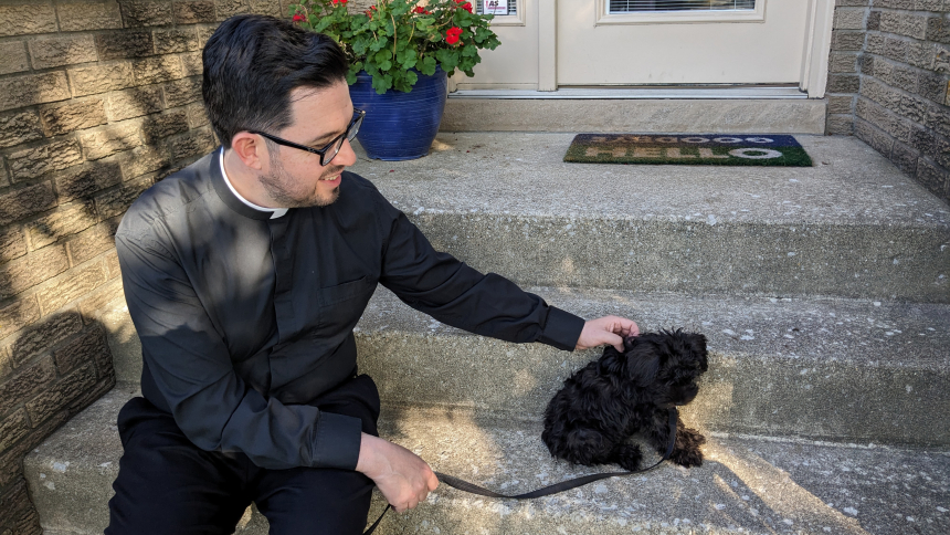 Father Leo Gajardo, pastor of St. Maria Goretti, sits on the porch step of the rectory in Dyer with his new puppy Sir. A member of the parish community for less than two months, the mini schnauzer is a "chill" companion and brings joy to those he meets. (Lynda J. Hemmerling photo) 