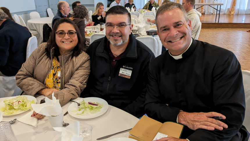 Father Matthew Kauth, from the Diocese of Charlotte, North Carolina, signs a book he wrote while Iliana Ortego and Julio Fonseca enjoy the first course of the family-style lunch served during the Diocesan Married Couples Retreat on Nov. 4. In addition to talks by Father Kauth, the day-long event at the Carmelite Shrine in Munster included Mass, adoration and confession. (Lynda J. Hemmerling photo)