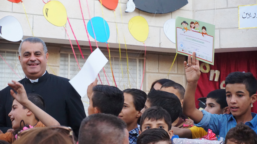 Father Rifat Bader, director of the Catholic Center for Studies and Media, is pictured in a 2016 file photo with Syrian refugee children during a graduation ceremony at the Latin Patriarchate School in Naour, Jordan. Father Bader told OSV News that a Nov. 5, 2023, decision by Jordan's Council of Churches to cancel Christmas festivities amid the ongoing Israel-Hamas war shows "solidarity with the people of Gaza." (OSV News photo/Dale Gavlak)