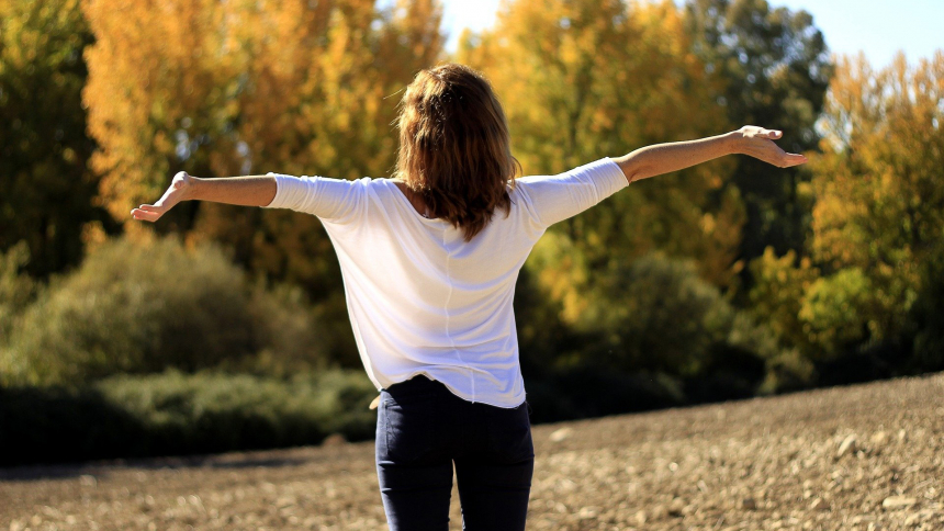 A woman stands in the sun with arms open, in a joyful expression of trust and surrender. (OSV News photo/Alfonso Cerezo)