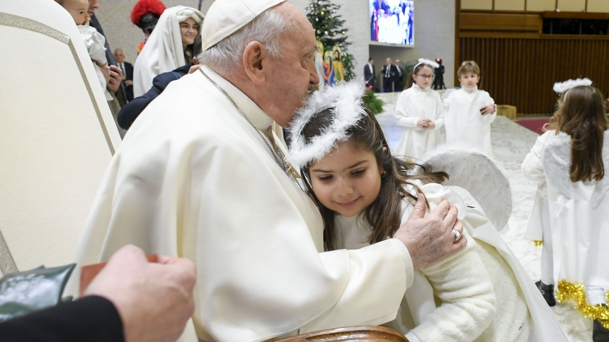 Pope Francis gets a hug from a girl playing an angel in a living Nativity scene in Rome after an audience Dec. 16, 2023, in the Paul VI Audience Hall at the Vatican. (CNS photo/Vatican Media)