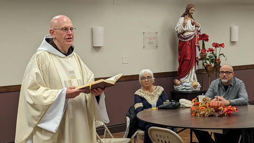Father Patrick Gawrylewski, OFM, reads a prayer while Elsa Cortez and Joel Cortez look on. The invocation was part of a Nov. 26 ceremony to name the Sacred Heart of Jesus Hall at Holy Name of Jesus in Cedar Lake. The name was chosen in recognition of the five-foot-tall Sacred Heart statue that was refurbished about six years ago. (Lynda J. Hemmerling photo)