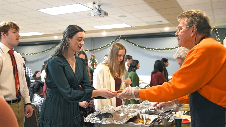 Junior nursing major Bryn Benzing (second from left) receives a Mexican sampler plate from volunteer Robert Bollman (right) as she is joined by other Valparaiso University students at the Advent Dinner event hosted at St. Teresa of Avila Catholic Student Center on Dec. 10. The annual pre-Christmas gathering staffed by church and ministry members featured snacks from various cultures, music and fellowship to Help support students through their finals. (Anthony D. Alonzo photo)