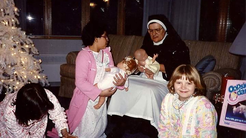 Nine-year-old Corrina Torres 'teaches' Sister Bernarda how to hold a baby doll as residents of the St. Joseph Carmelite Home open Christmas presents in 1988 at the East Chicago facility operated for 111 years by the Carmelite Sisters of the Divine Heart of Jesus. (Provided photo)