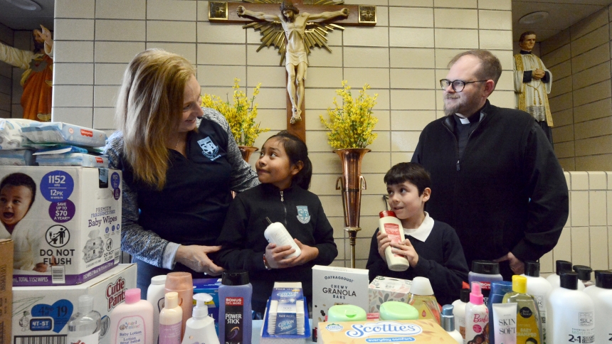 Encouraging almsgiving, St. John Bosco principal Nancy Repay (left) and SJB pastor Father Jeffrey Burton (right) praise students Jennifer Loza and Diego Duron for their efforts during a Catholic Schools Week personal care items drive for the needy on Feb. 2 in Hammond. The principal said the successful endeavor, led by the students with a sense of charity, will help assist the growing number of local residents experiencing financial strain. (Anthony D. Alonzo photo)