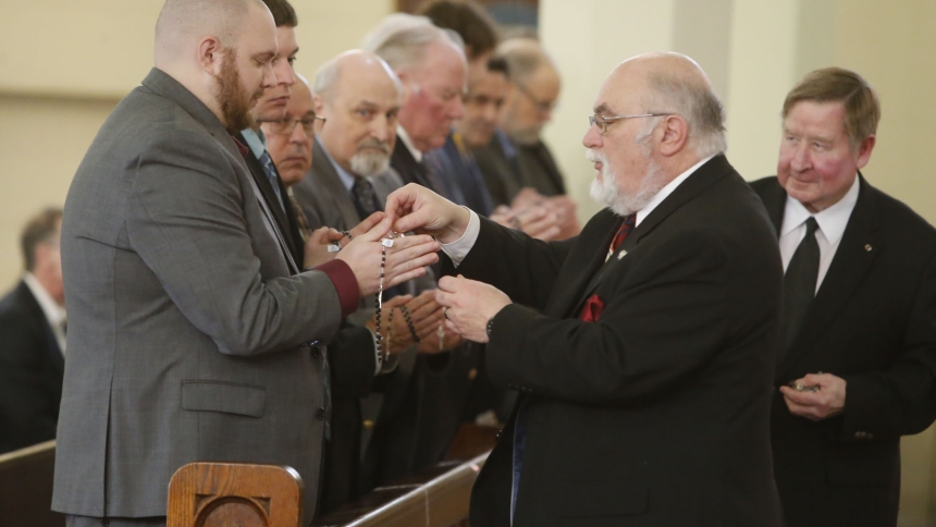 Bruce Garwood, Grand Knight for Queen of All Saints Council 12951, presents newly exemplified third-degree knights with rosaries during an initiation ceremony at St. Stanislaus Kostka parish on Feb. 11. (Bob Wellinski photo)