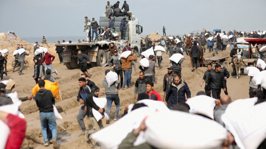 Palestinians carry bags of flour they grabbed from an aid truck  in Gaza City Feb.19, 2024, near an Israeli checkpoint. Gaza residents face crisis levels of hunger amid the ongoing conflict between Israel and Hamas. (OSV News photo/Kosay Al Nemer, Reuters)