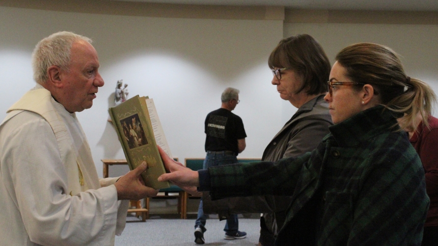 Father Frank DeSiano, of Washinton, DC, president of the Paulist Fathers and one of the Eucharist preachers named by the USCCB, holds the Bible for Tina Pysh and Kristin Kantrowski to reverence during the first session of a three-day Eucharistic Mission hosted by St. Paul in Valparaiso on April 23. Morning and evening sessions were held with four speakers, folloiwed by fellowship. (Marlene A. Zloza photo)