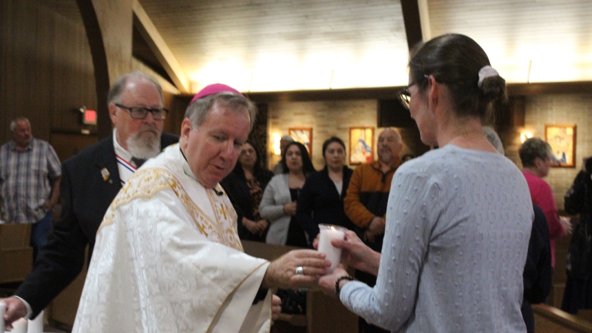 Bishop Robert J. McClory presents a candle in remembrance of her child to Chris Petro of Chesterton, a parishioner at St. Patrick, during the Mass for Pregnancy and Infant Loss on May 5 at Queen of All Saints in Michigan City. Petro lost Baby Petro through miscarriage, and joined dozens of other parents at the annual liturgy on Bereaved Mother's Day. (Marlene A. Zloza photo).