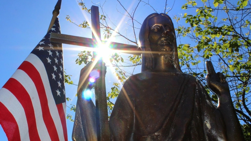 Sun shines through a statue of Christ on a grave marker alongside an American flag at St. Mary Catholic Cemetery in Appleton, Wis., in this 2018 photo. The U.S. Conference of Catholic Bishops' annual Religious Freedom Week takes place June 22-29, 2024. (OSV News photo/Bradley Birkholz)
