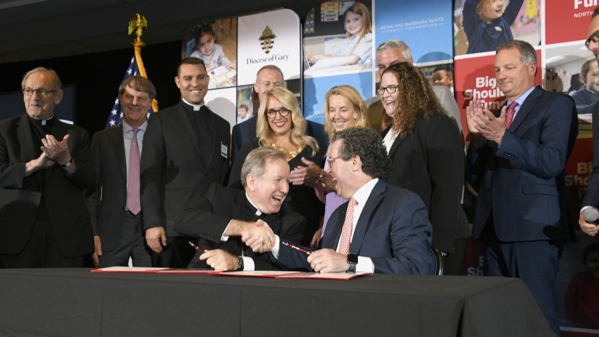 Bishop Robert J. McClory (lower left), sits at the signing table and shakes the hand of Joshua Hale (lower right), president and chief executive officer of the Big Shoulders Fund, at the event announcing the 10-year commitment by The Dean and Barbara White Family Foundation to donate $150 million to the non-profit, on June 12 at the Lighthouse Restaurant in Cedar Lake. The donation is the largest single gift to Catholic pre-kindergarten through grade 12 education in history and will be invested in the quali