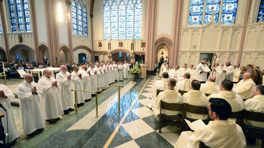 At the Cathedral of the Holy Angels in Gary, Bishop Robert J. McClory (at right) says prayers over 15 men who stand at the sanctuary during the Mass of Ordination to the Diaconate on June 8. In his homily, the bishop said the clergymen should serve, as St. Mother Teresa of Calcutta recommended, with "JOY - for Jesus, Others and Yourself." (Anthony D. Alonzo photo)