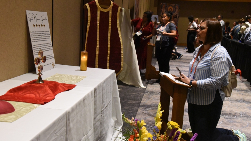 An attendee of the National Eucharistic Congress kneels in prayer July 19, 2024, before relics of St. Manuel Gonzalez, known as the "bishop of the abandoned tabernacle," in the congress's relic chapel at the Indiana Convention Center in Indianapolis. (OSV News photo/Sean Gallagher, The Criterion)