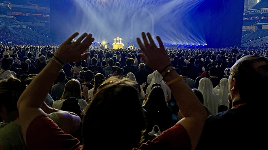 A worshipper raises their hands as the Blessed Sacrament is displayed on an altar in a large monstrance at Lucas Oil Stadium during a revival and adoration session of the 10th National Eucharistic Congress in Indianapolis on July 17. Pilgrims at the congress shared memorable moments in communal prayer, private devotion and lively fellowship among expereinces some spoke about as life-changing manifestations of the Holy Spirit. (Anthony D. Alonzo photo)