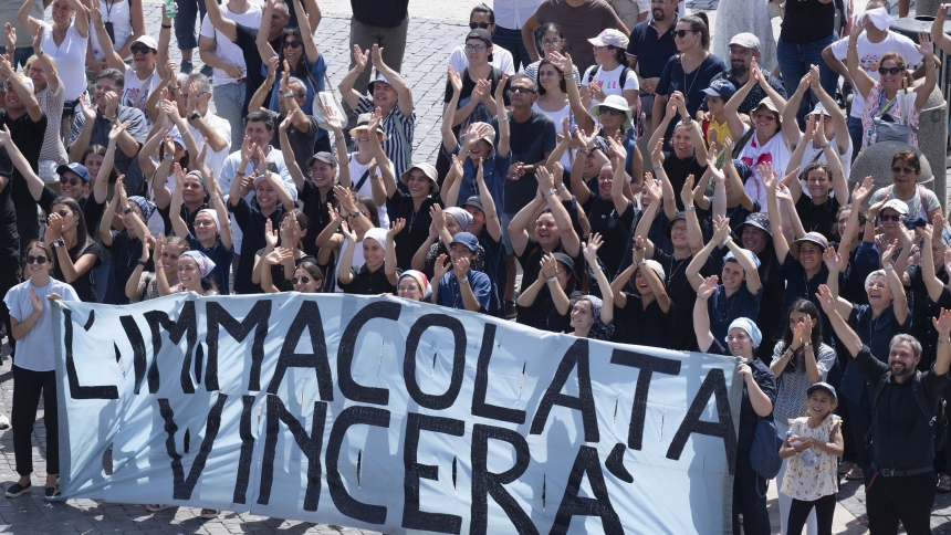 Standing behind a banner that says in Italian, "The Immaculate will conquer," a quote from St. Maximilian Kolbe, a group of people wave and cheer in St. Peter's Square at the Vatican after joining Pope Francis for the recitation of the Angelus prayer Aug. 15, 2024, the feast of the Assumption of Mary. (CNS photo/Vatican Media)