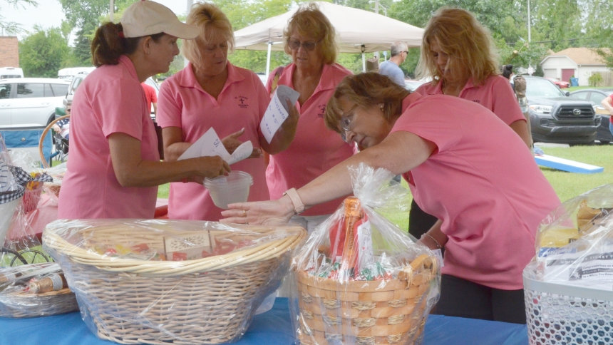 Members of the St. James the Less Women's Guild set up a table of gift baskets for a raffle during the parish picnic on Aug. 18. The guild works together in a variety of activities at the church and assists with fundraising events. (Erin Ciszczon photo)