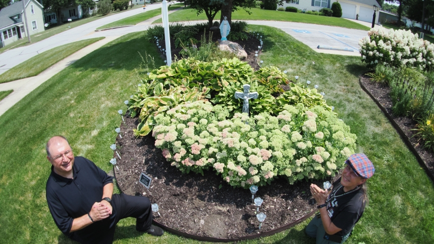 Father Stephen Loncar, pastor of St. Thomas Aquinas, and parishioner Bernadette Schonka pose along side the parish’s new solar rose Rosary Garden on Aug. 3. The garden blessing will be part of the Blessed Mother’s birthday celebration on Sept. 8. (Deacon Bob Wellinski photo)