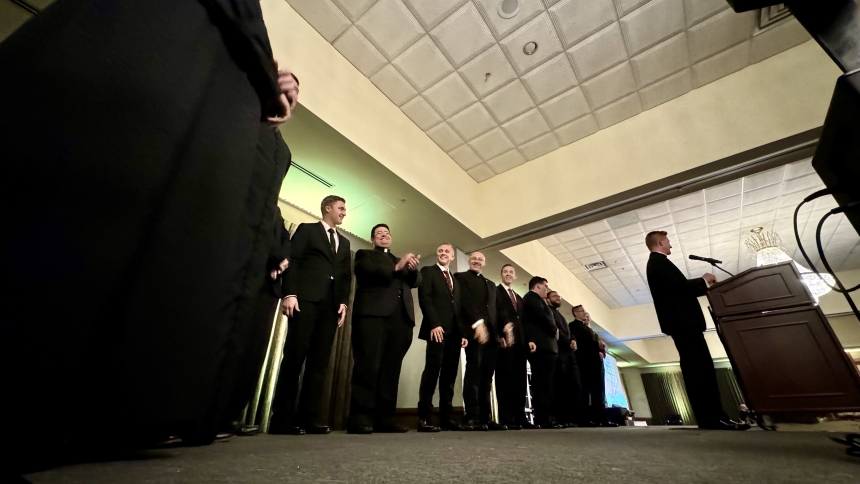 Seminarians gather on stage bookended by vocations office officials Father Jacob McDaniel (left), chaplain of St. Teresa Center for Catholic Students in Valparaiso and Father Nathaniel Edquist (right), pastor of Holy Family Parish in LaPorte during the annual Black Tie White Collar gala on September 20 at Avalon Manor Banquet Center in Merrillville. Supporters of priestly vocations prayed, dined, danced, played games, bid on auction items and generally had fellowship with the discerners. (Anthony D. Alonzo