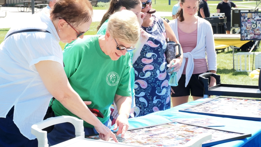 Bridget Provenzano and Mary Persyn look over historic photos of St. Teresa of Avila Catholic Student Center during the 50th anniversary picnic on August 25. (Deacon Bob Wellinski photo)