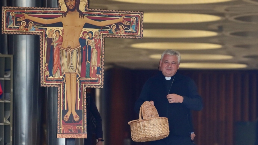 Cardinal Konrad Krajewski, prefect of the Vatican's Dicastery for the Service of Charity and papal almoner, stands with a basket at the entrance of the Paul VI Hall in Vatican City, where Synod on Synodality delegates meet, to collect alms on Oct. 7, 2024, the first anniversary of Hamas' attack on Israel and subsequent Israel-Hamas war. That same night the funds were received by Vatican's embassy in Jerusalem and were transferred to the Holy Family Parish in Gaza City. (OSV News photo/courtesy Dicastery for