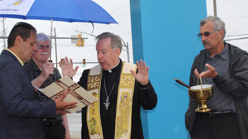 Bishop Robert J. McClory offers a blessing at the new Society of St. Vincent de Paul Gary District Council headquarters in Hammond on Sept. 22. Despite a light rainfall, the bishop gamely added some holy water at the gathering with the help of (from left) Deacon Albert Burgos, SVDP member Dan McKern, the bishop and SVDP Gary District Council president Mike Martinelli. (Marlene A. Zloza photo)