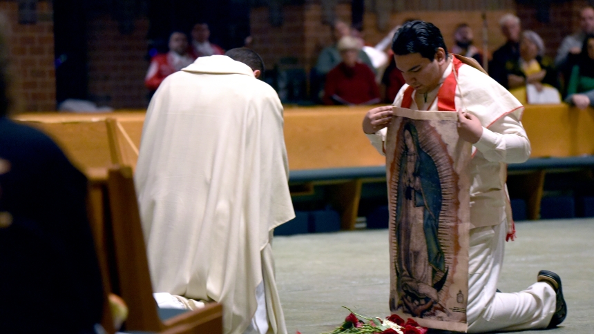 Portraying St. Juan Diego, Alex Muñoz (right) displays a tilma and roses, signs of a Marian apparition, to the character of Bishop Juan de Zumarraga (of Mexico City, New Spain), portrayed by Father Robert Ross, on the Feast of Our Lady of Guadalupe, Dec. 12, in Schererville. About 300 faithful gathered to celebrate the "Patroness of the Americas" at St. Michael the Archangel where Mass celebrant Bishop Robert J. McClory lauded the Blessed Mother's intercessory power and desire to bring us closer to her Son.