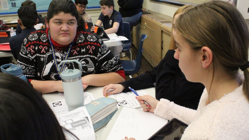 Eighth graders Olivia Vega and Lillian Wanek discuss the recent performance of the four stocks their classroom chose to 'buy' at the start of the Stock Market Program at Big Shoulder Schools in Northwest Indiana during a class on Dec. 18. Wanek proposed divesting of the Chase stock and adding a foreign stock to provide more diversification, and the class agreed. The program will extend through April. (Marlene A. Zloza photo)