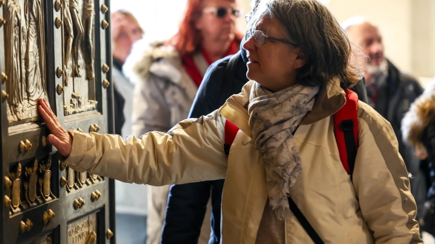 A visitor touches the Holy Door of St. Peter’s Basilica on Christmas Day, Dec. 25, 2024, after it was opened by Pope Francis during Christmas Mass the night prior to mark the start of the Holy Year 2025. (CNS photo/Lola Gomez)