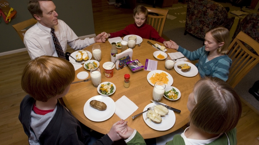 A family prays before eating a meatless meal of baked potatoes and salad at their home. As Catholics, we undertake the Lenten practices of prayer, fasting and almsgiving seeking spiritual conversion as we journey to the cross with Christ. (OSV News photo/Nancy Wiechec)  
