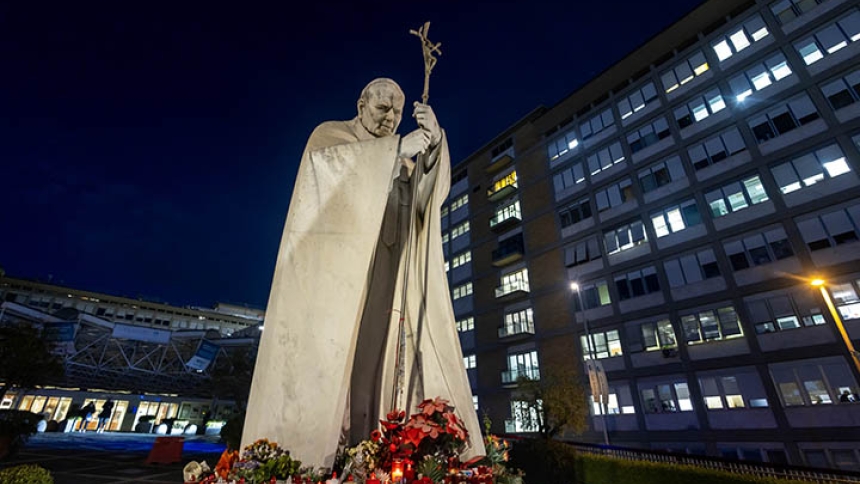A statue of St. John Paul II, with flowers and candles at its base, is seen outside of Rome's Gemelli hospital in the early evening Feb. 15, 2025, the day after Pope Francis was admitted for tests and treatment of a respiratory tract infection. (CNS photo/Pablo Esparza)