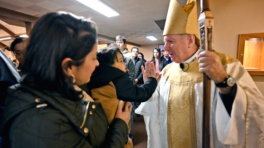St. Francis Xavier parishioner Elizabeth Zepeda (left) holds her three-year-old son Oliver Zepeda (center) as Bishop Robert J. McClory imparts a blessing and a high-five at the conclusion of Mass during the diocesan shepherd's pastoral visit to Lake Station on Feb. 2. Gary bishops have made pastoral visits key parts of their ministry and Bishop McClory strives to connect with the diocesan faithful in four counties as best as his schedule permits. (Anthony D. Alonzo photo)