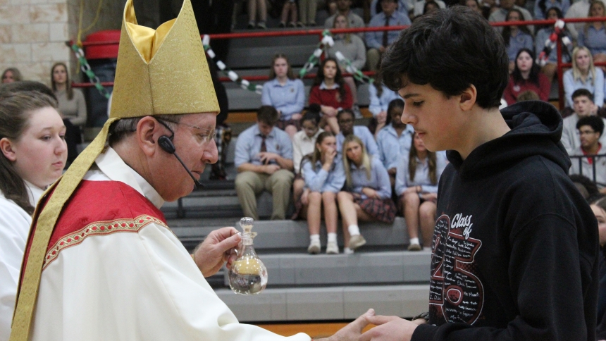 Bishop Robert J. McClory accepts a cruet of water from Vincenzo Pomilia, an eighth grader at St. John the Evangelist School in St. John, during a Catholic School Week Mass at Andrean High School in Merrillville on Jan. 31. Also carrying up the offertory gifts at the Mass were Arianna Patiks, and eighth grader from St. Michael School in Schererville, and Siboney Sanchez-Mojica, an eighth grader at Aquinas Catholic Community School in Merrillville. (Marlene A. Zloza photo)