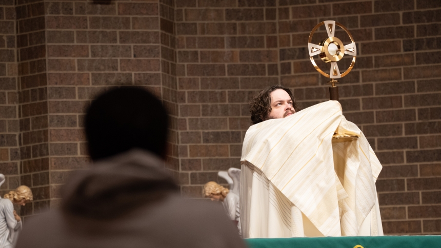 Father Gregory Bim-Merle, pastor of St. James the Less church, raises a monstrance containing the Blessed Sacrament during a benediction at the weekly Eucharistic Adoration on the evening of Feb. 17 in Highland. At churches and chapels throughout the diocese, opportunities for the worship of the Eucharisitc Lord have been increasing as a response to expressed interest of the faithful and the efforts of local clergymen. (Anthony D. Alonzo photo) 