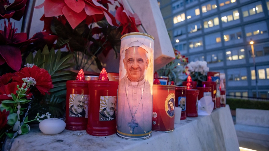 Votive candles and flowers are seen at the base of a statue of St. John Paul II outside Rome's Gemelli hospital Feb. 19, 2025, where Pope Francis is being treated for double pneumonia. (CNS photo/Pablo Esparza)